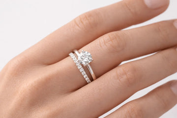  Woman's hand wearing stacked wedding band and engagement ring in traditional order