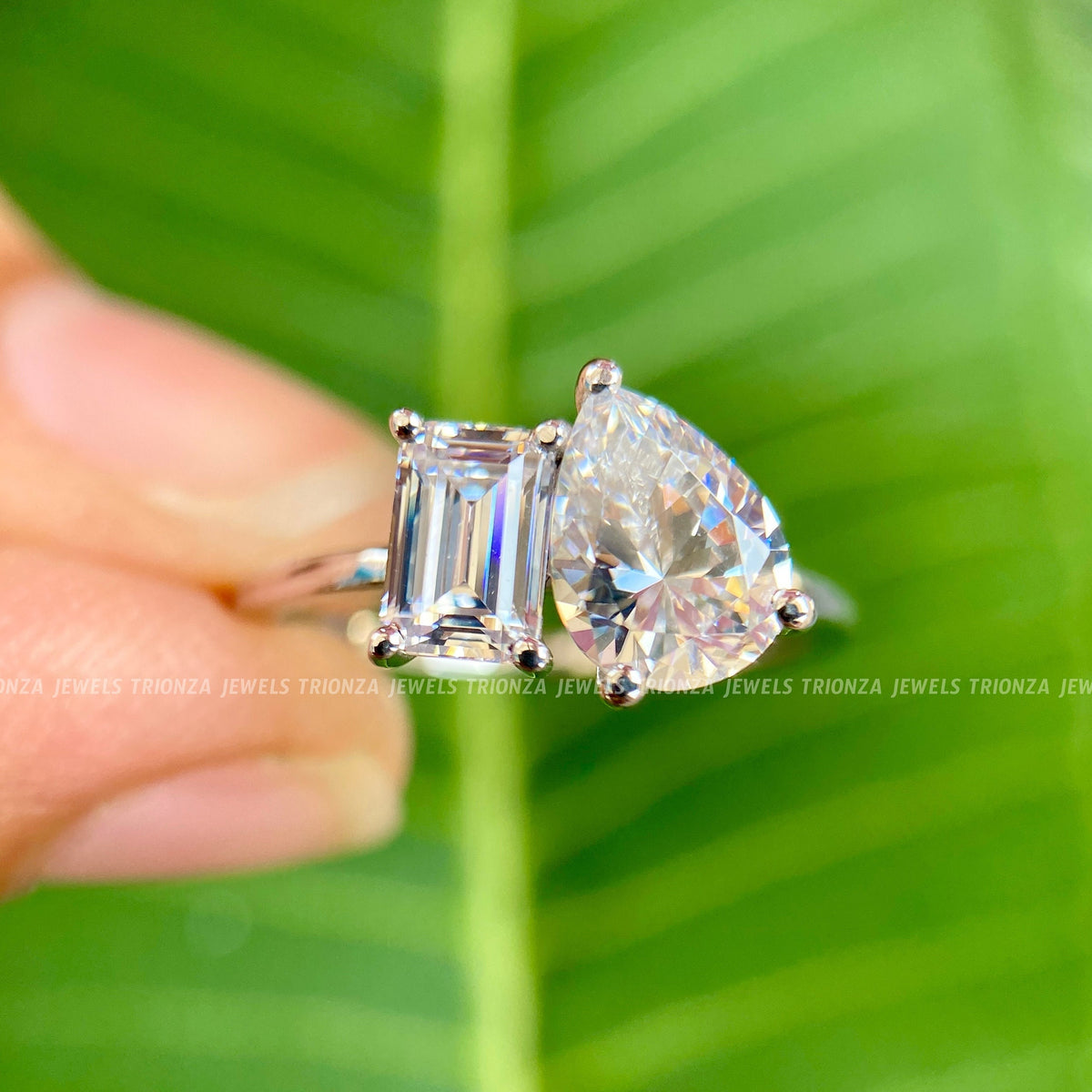 Close-up of the 6x8mm pear cut and 4x6mm emerald cut moissanite stones in prong settings
