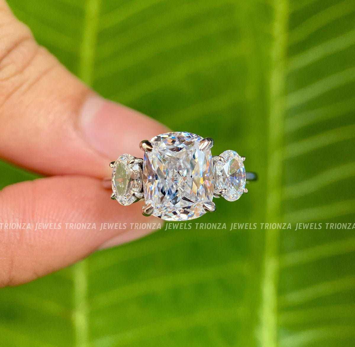 Cushion cut moissanite engagement ring with oval three stone accents set in 14K gold