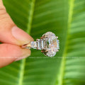 Side princess and emerald cut moissanite stones accenting the elongated oval center gem