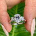 Oval cut moissanite three stone engagement ring featuring round prong set side stones