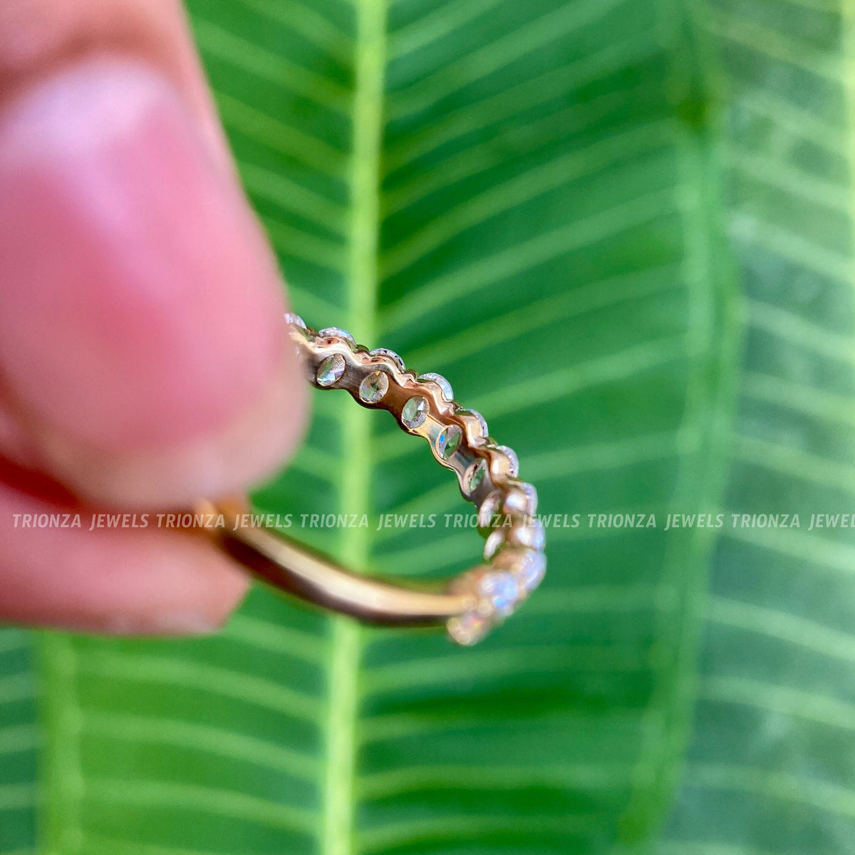 Woman wearing the oval moissanite gold band stacked alongside other rings