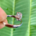 Oval moissanite wedding ring shown alongside its jewelry box and smooth fabric