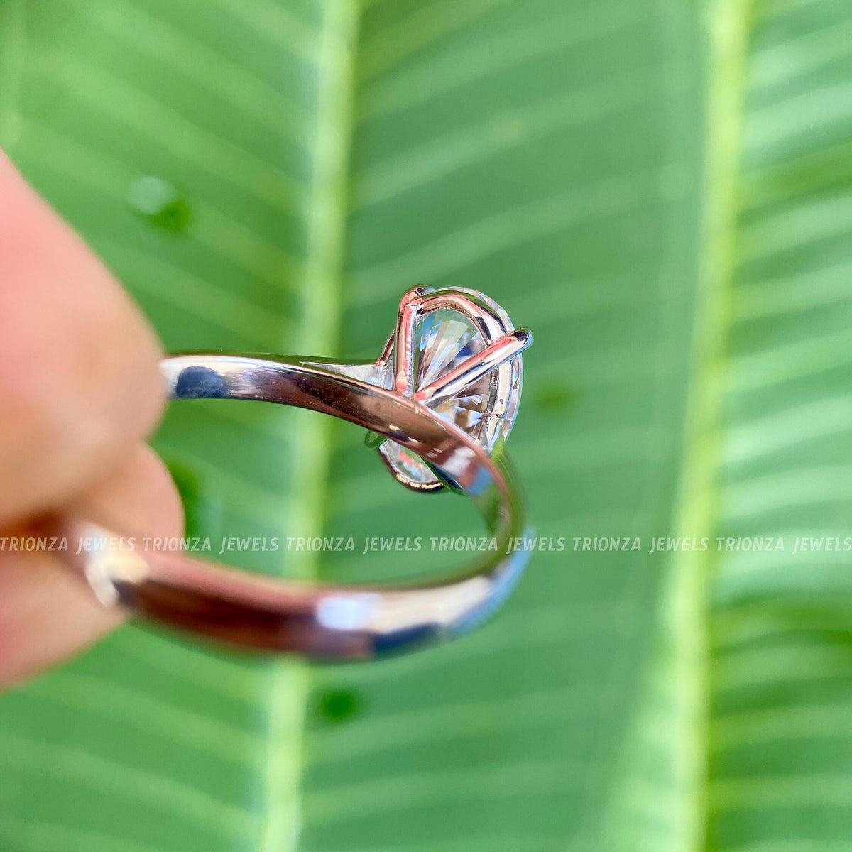 Oval moissanite wedding ring shown alongside its jewelry box and smooth fabric
