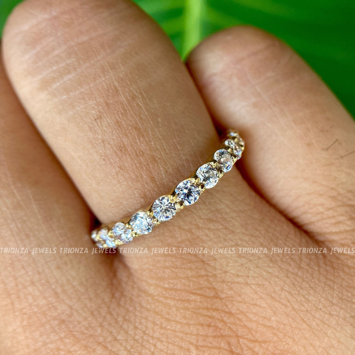 Close-up of the single prong setting securing each round moissanite stone in the band