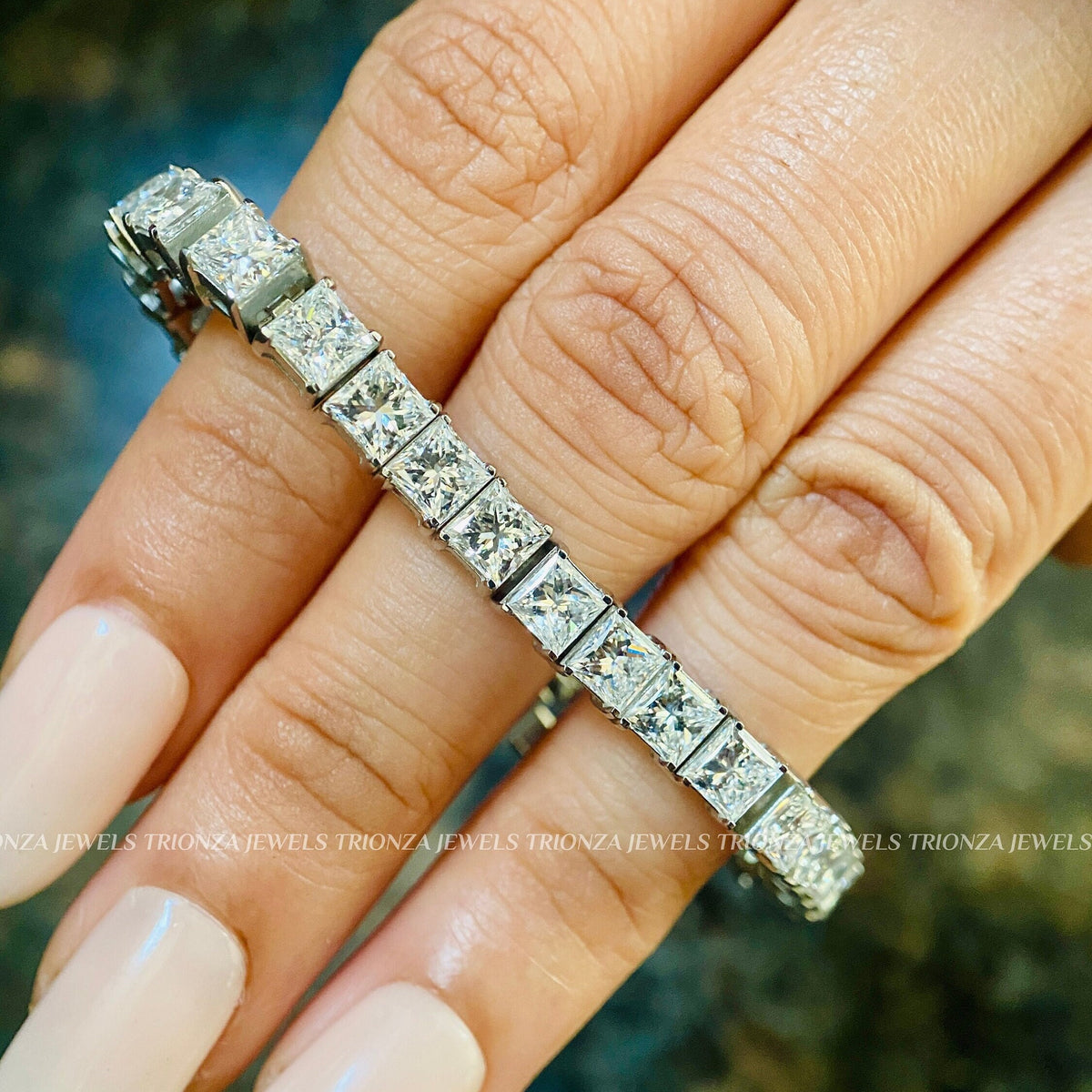 Stackable infinity bracelet featuring princess cut diamonds set in polished gold prongs