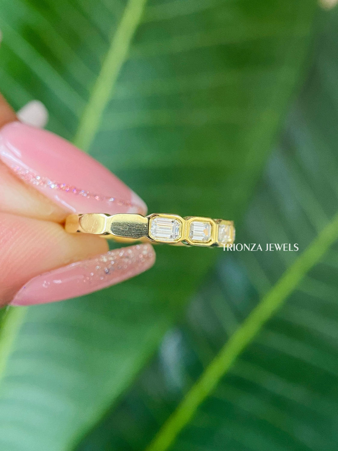 Emerald cut moissanite half eternity band featuring an east-west bezel setting in 14K yellow gold