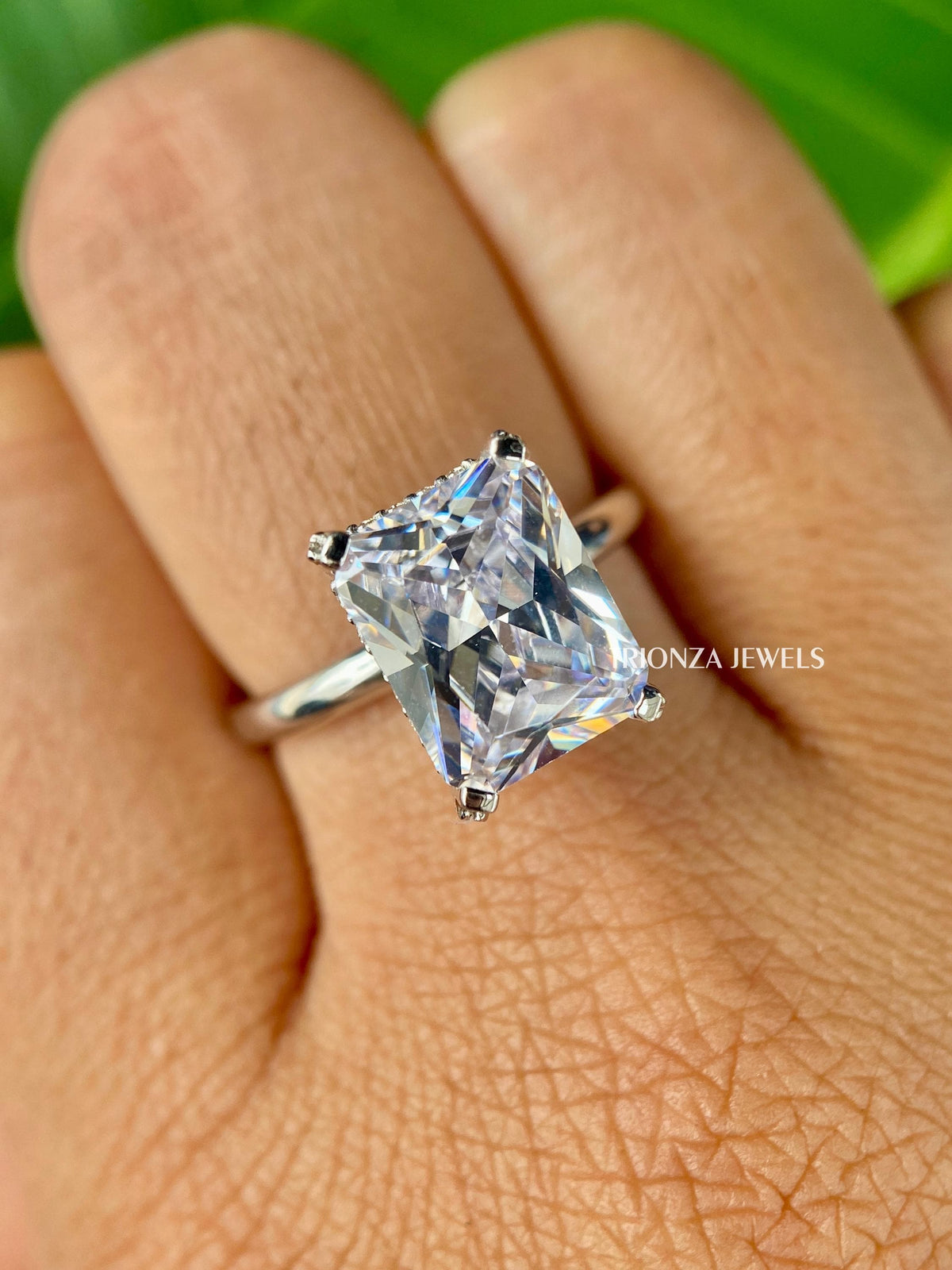 Close-up of the radiant cut center stone with round cut side stones in a hidden halo setting