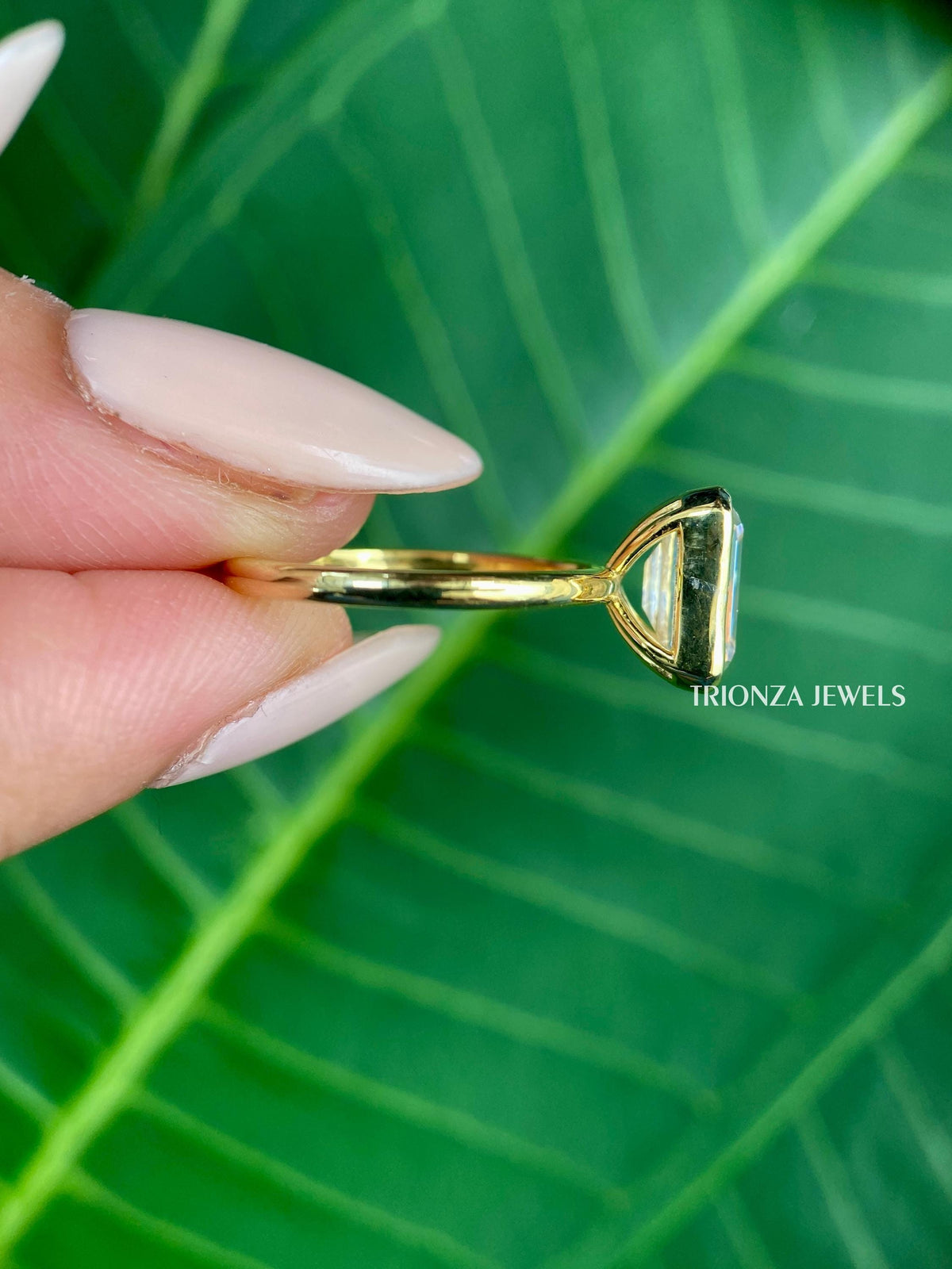 Close-up of the bezel setting securing the emerald cut moissanite in solid gold