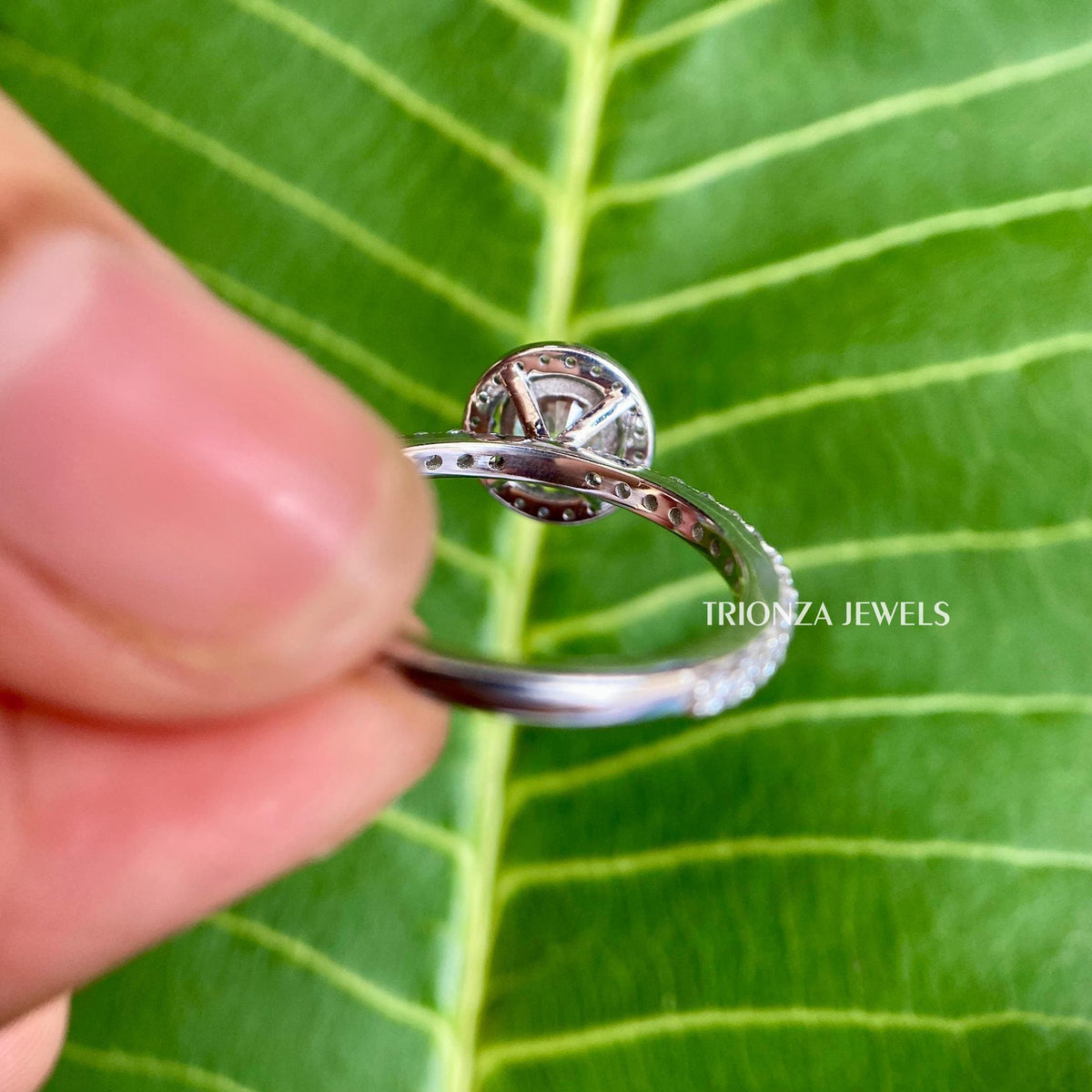 Pave set side stones surrounding the round cut moissanite in a handmade halo design
