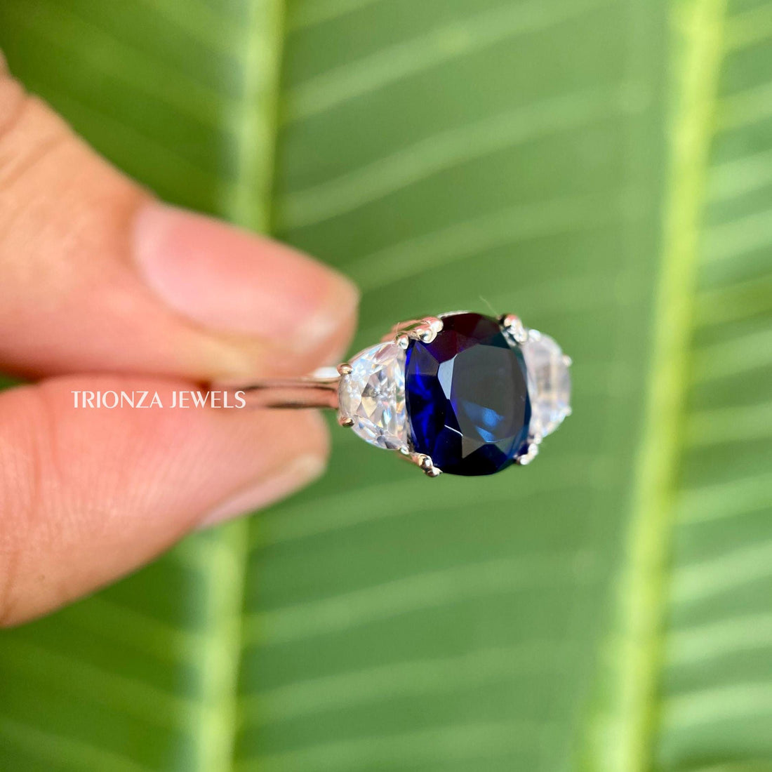 Blue cushion cut moissanite three stone ring featuring half moon side stones set in gold