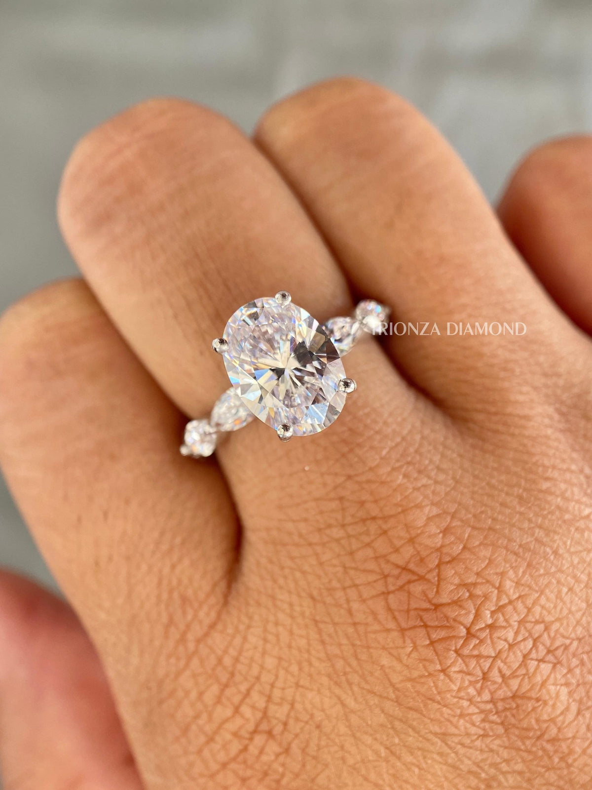 Oval cut lab diamond engagement ring with marquise accents and a hidden halo setting
