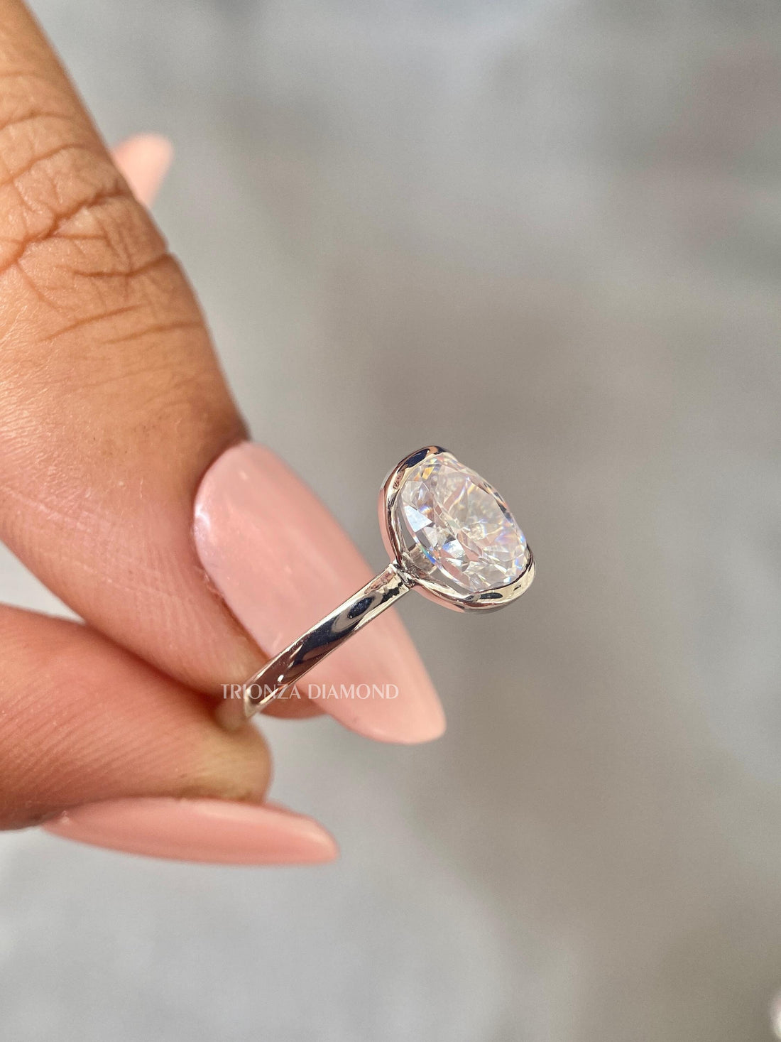 Oval cut lab grown diamond ring featuring a half bezel solitaire setting in 14k gold