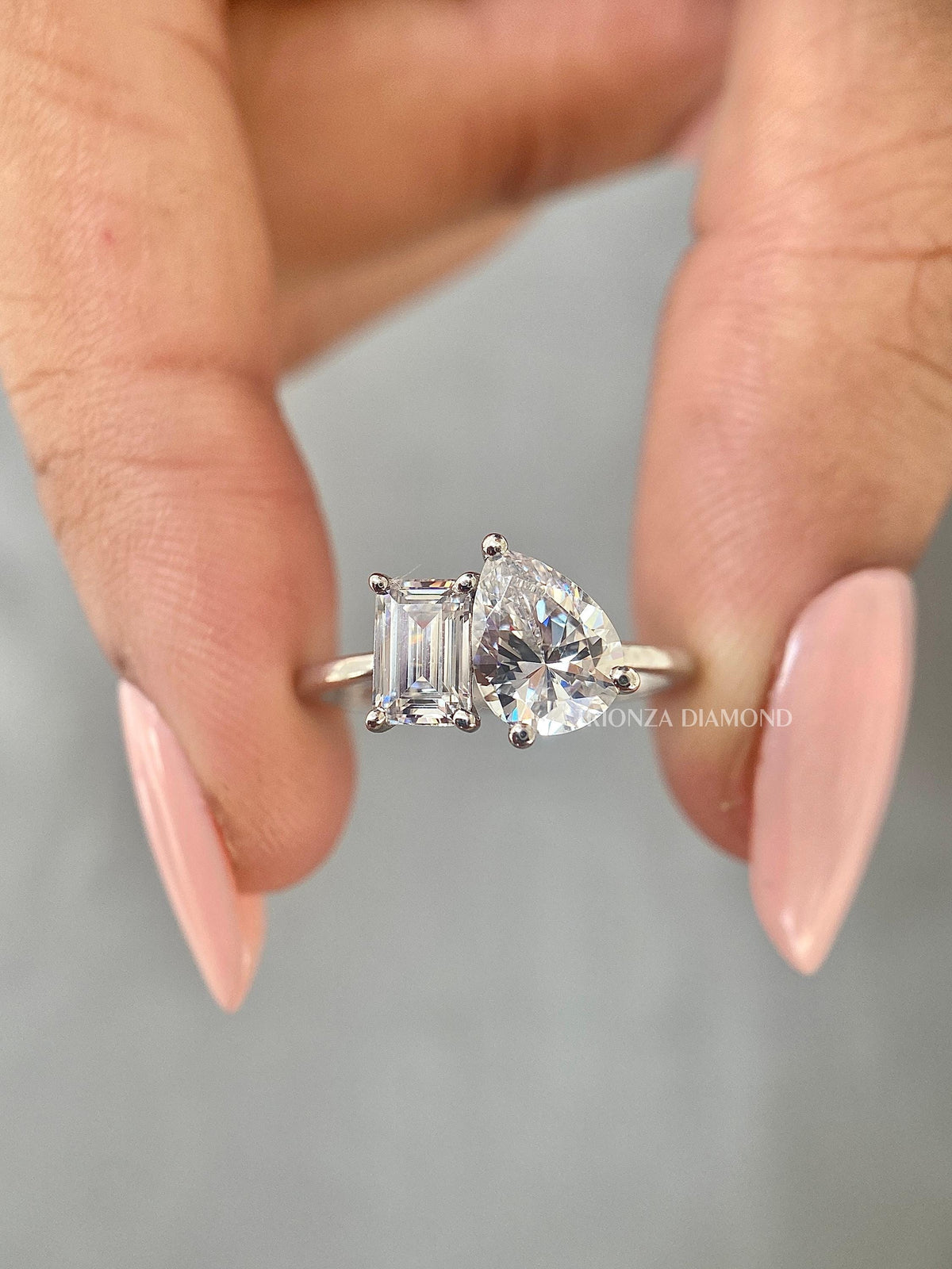 Two stone engagement ring showcasing an emerald cut and pear cut diamond side by side