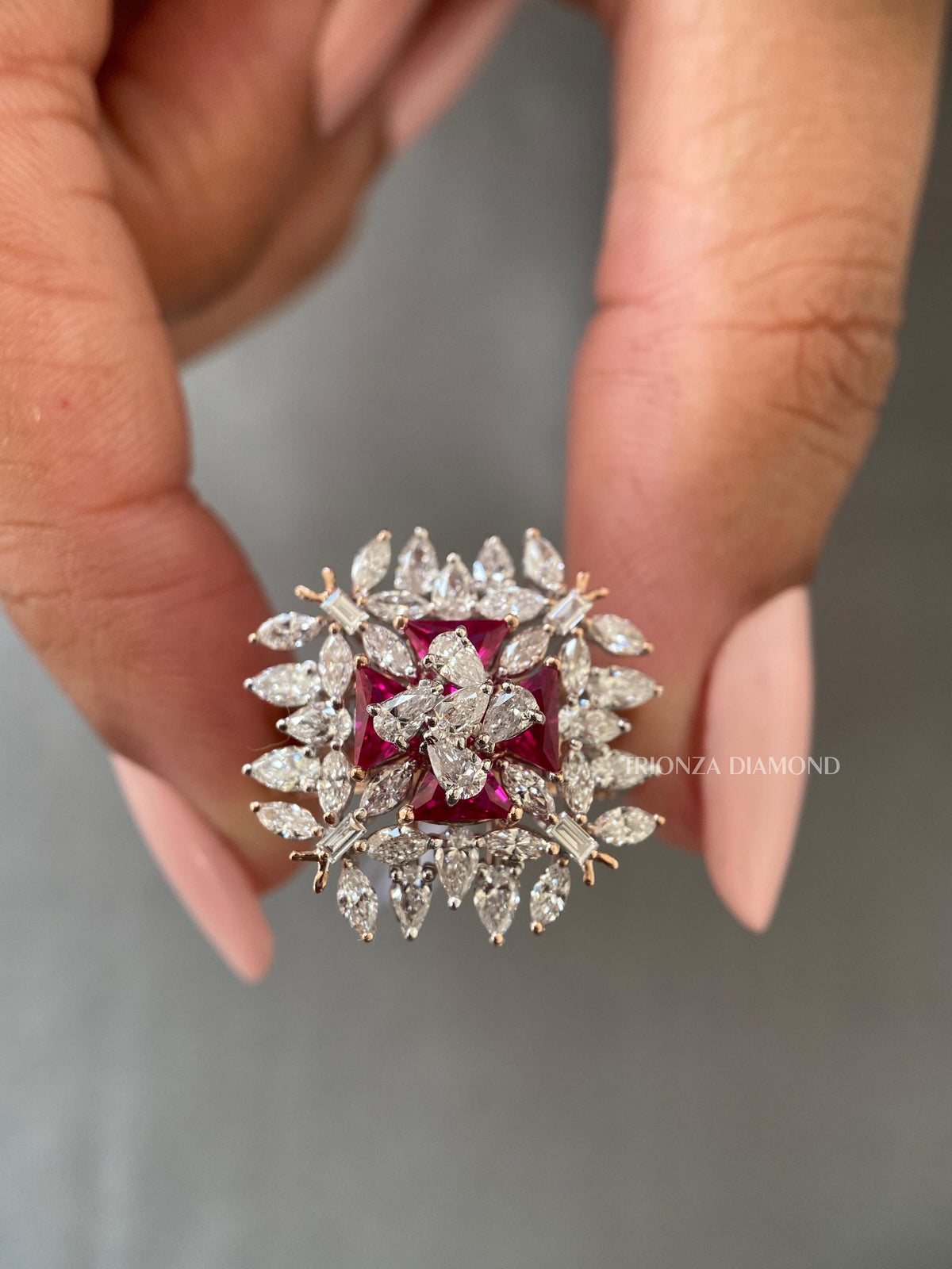 Woman wearing the unique gold cluster ring featuring pink triangle cut accent stones