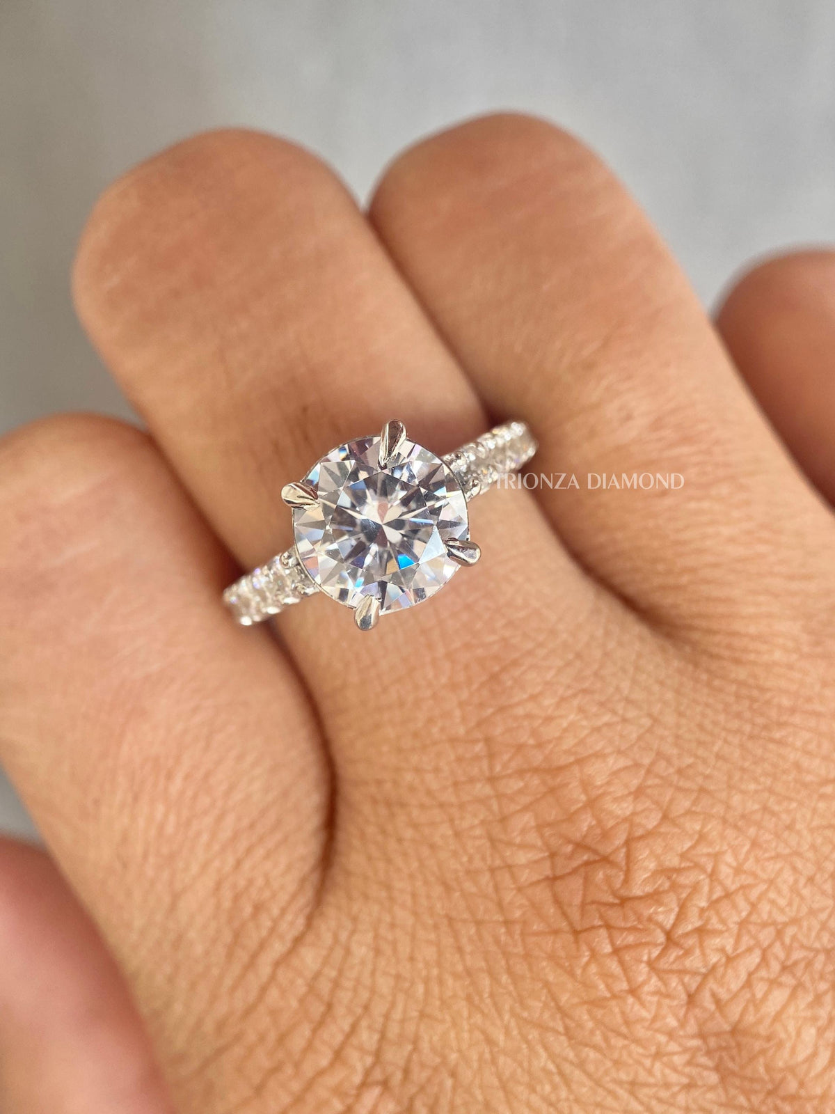 Personalized engagement ring with round cut side diamonds set in a pave shank design