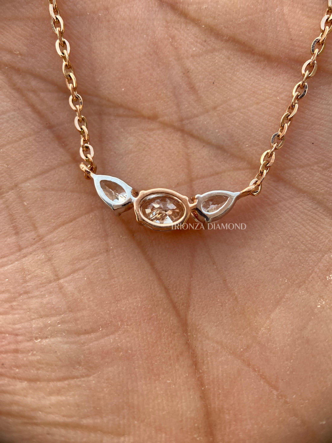 Oval pear three stone diamond pendant featuring a flower-inspired handcrafted 14K gold setting