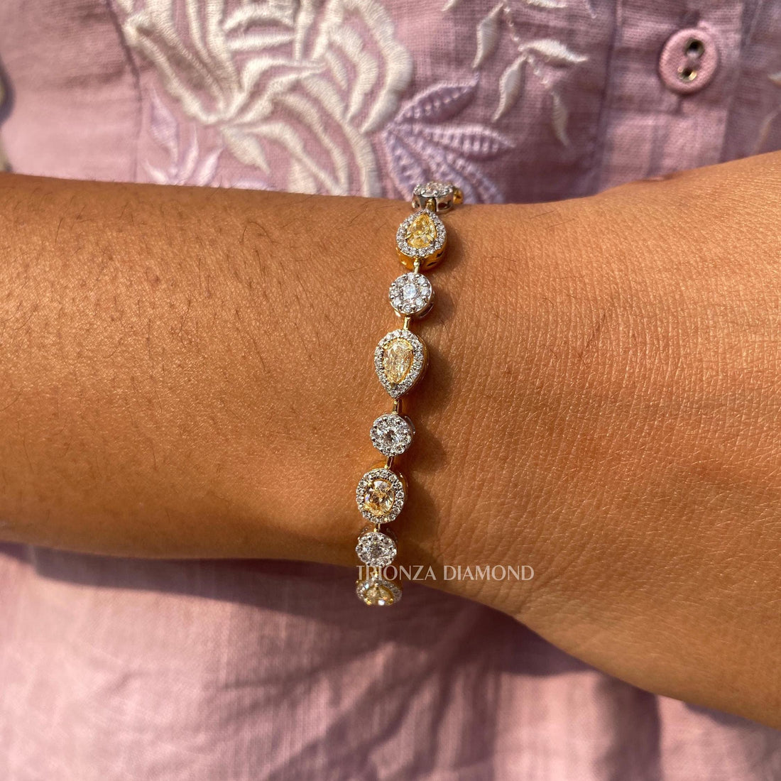 Fancy yellow lab grown diamond tennis bracelet featuring pear, oval, and round cut stones in 14K gold