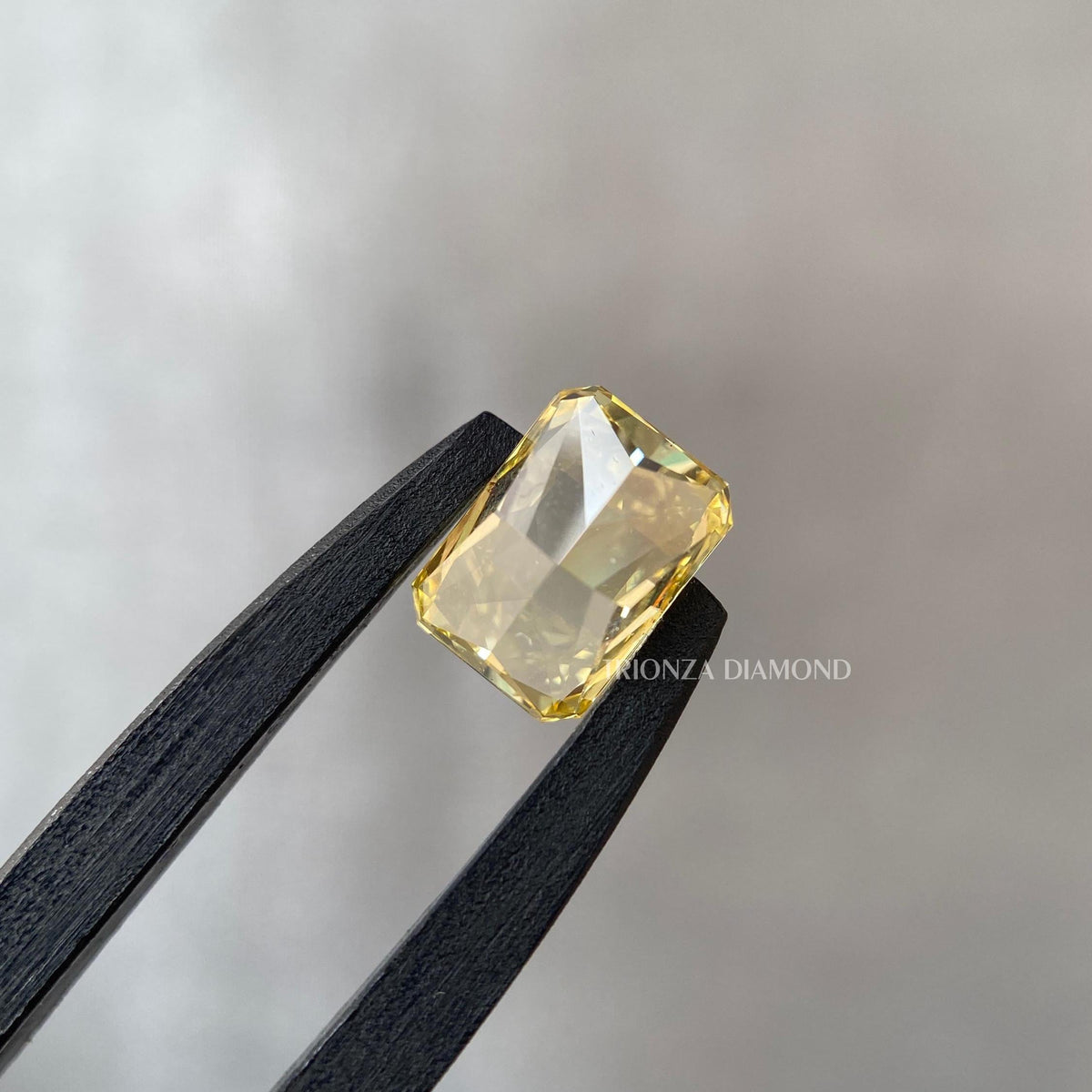 Loose radiant cut diamond shown against a contrasting background to showcase its vivid yellow hue