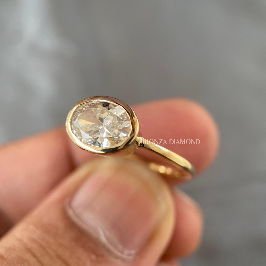 East west oval diamond engagement ring set in a sleek bezel design