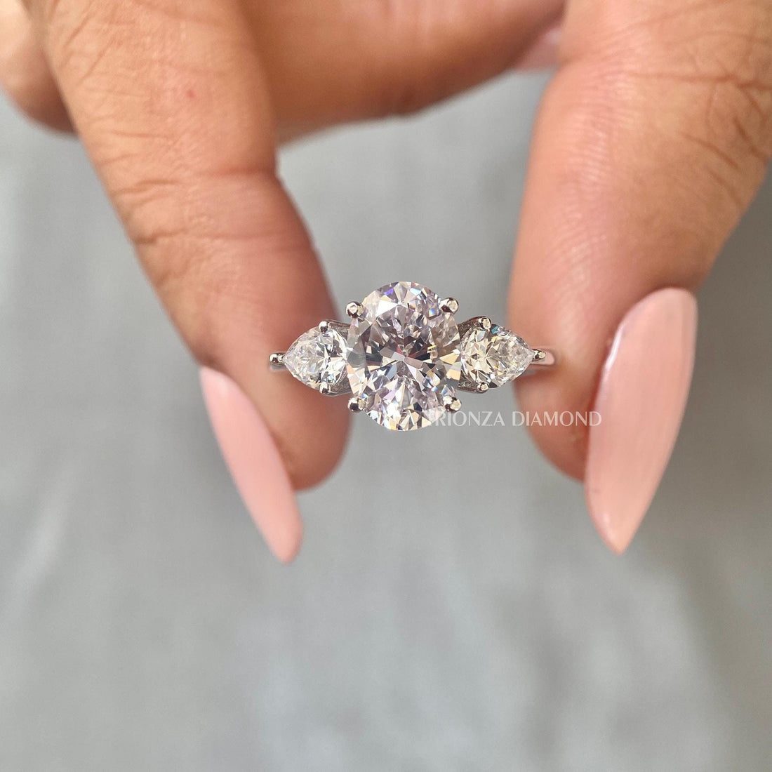 Oval lab grown diamond engagement ring featuring pear cut side stones in a three stone design