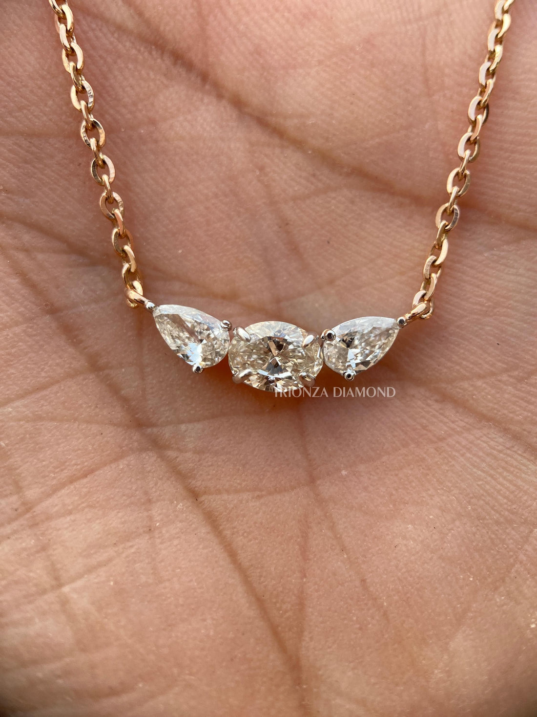 Oval pear three stone diamond pendant featuring a flower-inspired handcrafted 14K gold setting