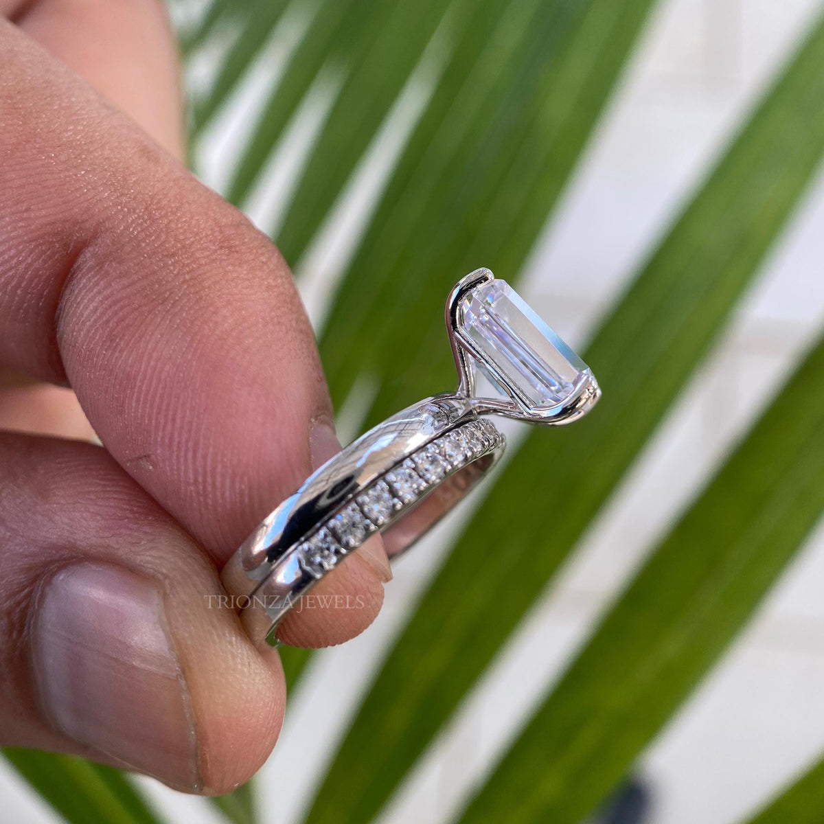 Close-up of the emerald cut moissanite ring showing prong and halo setting details