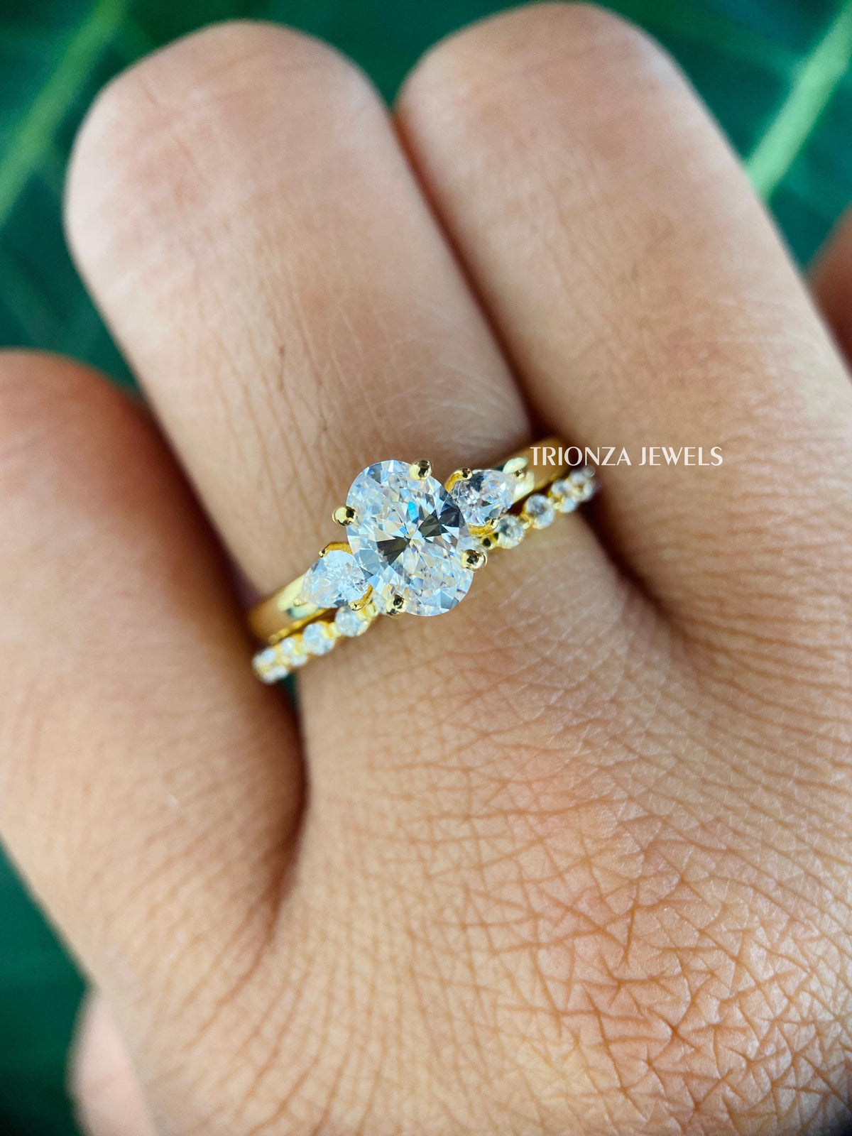 Oval cut three stone moissanite engagement ring paired with a matching 14k yellow gold wedding band