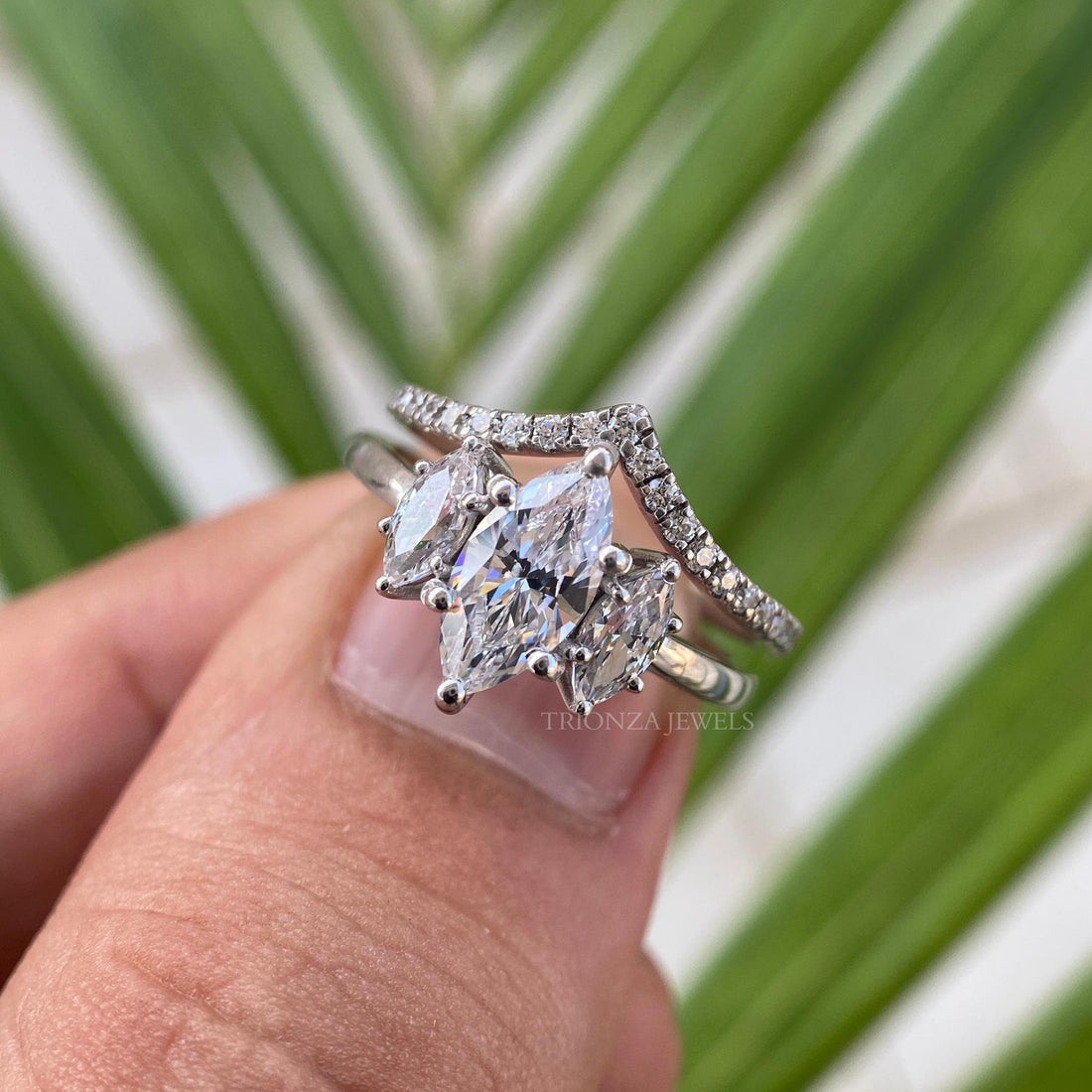 Three stone marquise moissanite bridal set ring showcasing a chevron band design in white gold