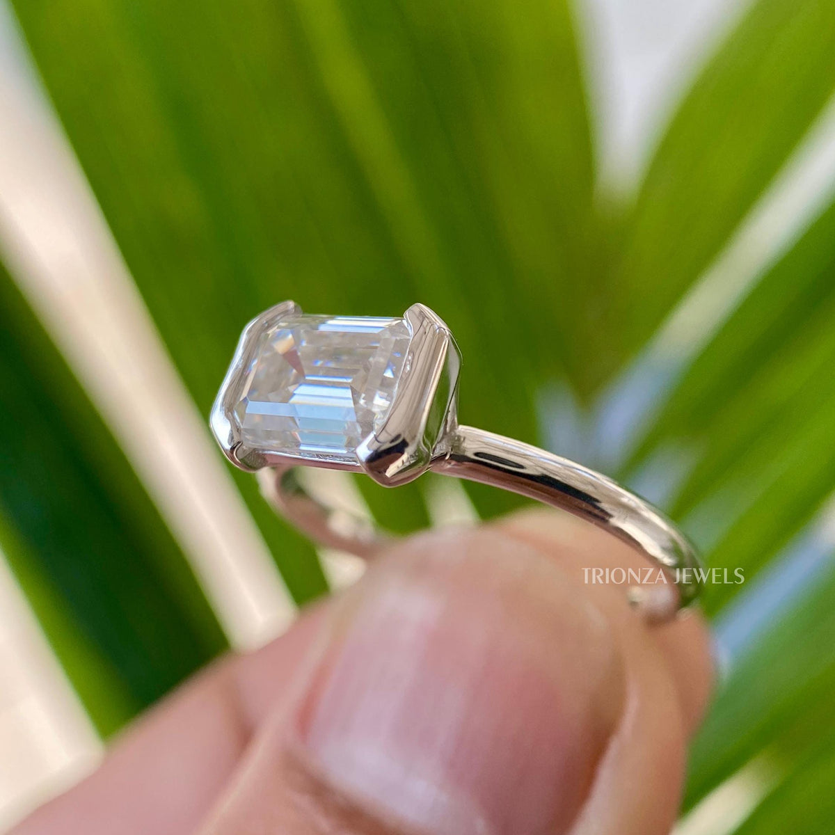 Close-up of the 1.5 CT colorless VVS emerald cut moissanite stone set horizontally