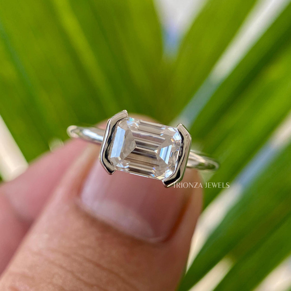 East-West emerald cut moissanite ring featuring a half bezel setting in 14K solid gold
