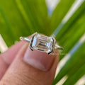East-West emerald cut moissanite ring featuring a half bezel setting in 14K solid gold