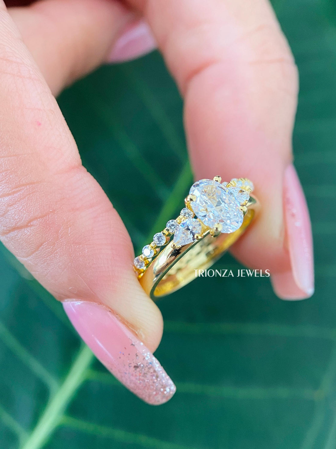 Oval cut three stone moissanite engagement ring paired with a matching 14k yellow gold wedding band