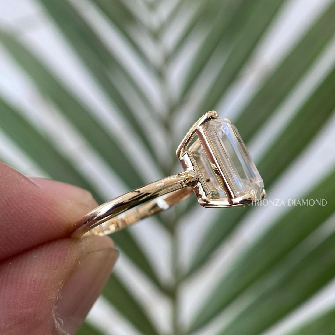 Emerald cut moissanite engagement ring displayed to show its solitaire bezel setting