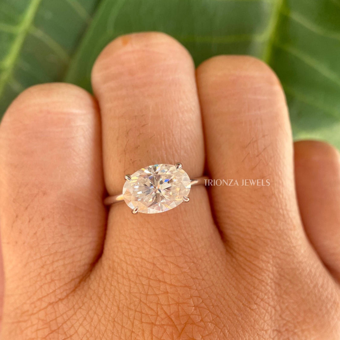 East to west oval moissanite ring displayed as a two tone solitaire design