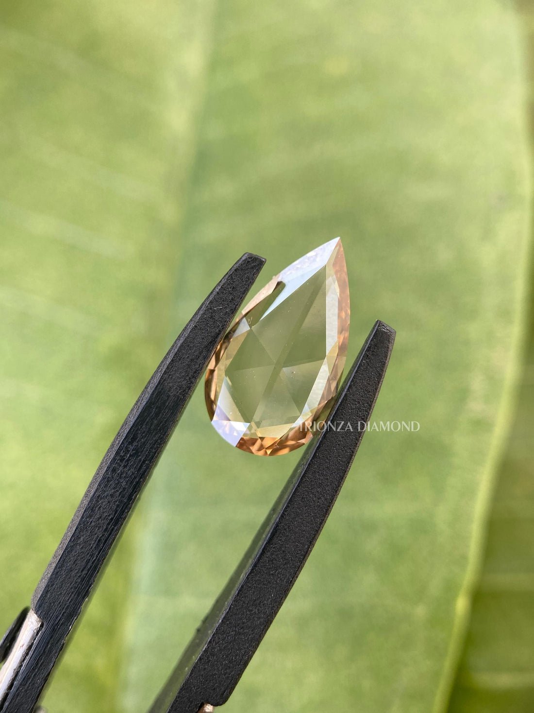 Pear rose cut lab grown diamond in champagne color displayed to show its faceted brilliance
