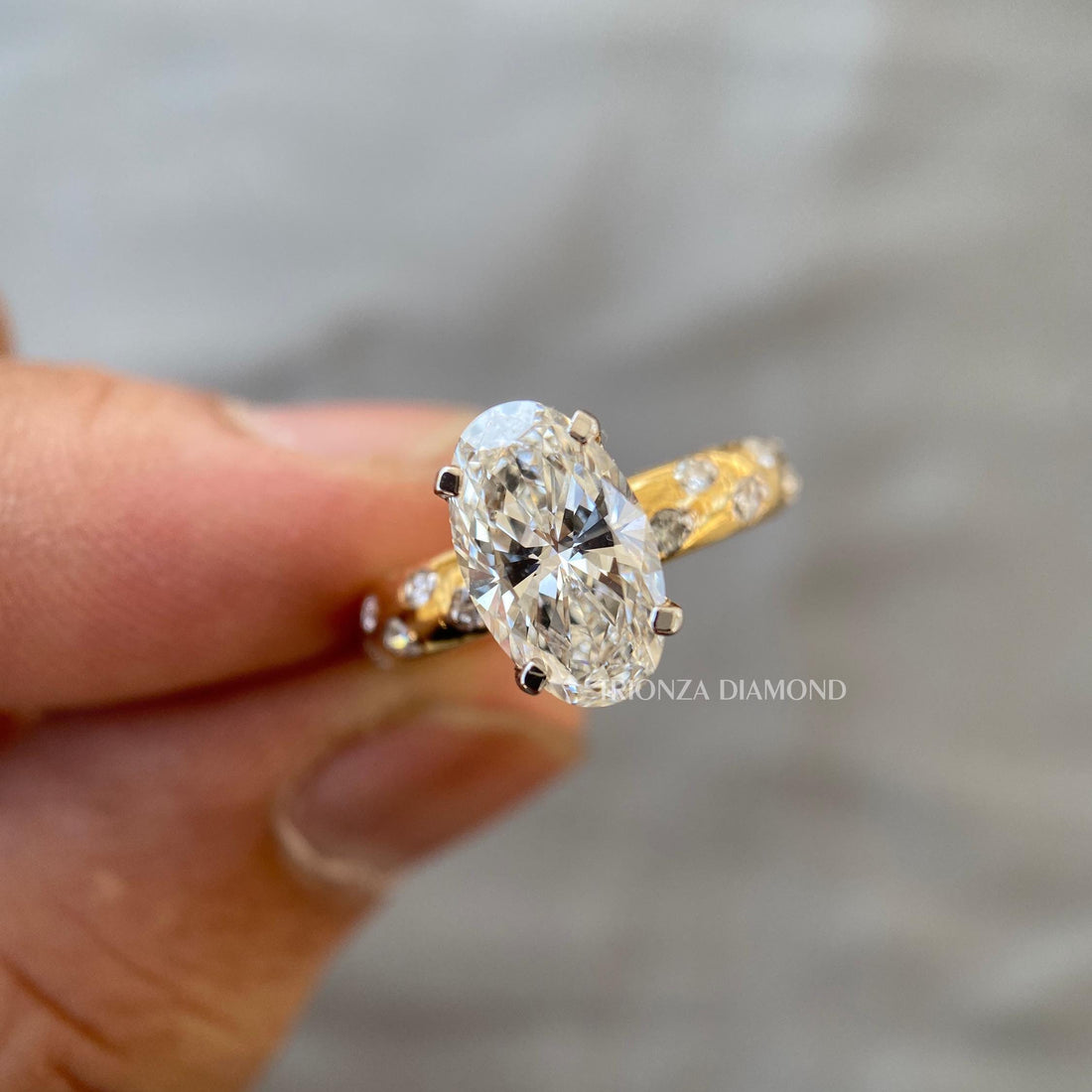 Elongated oval lab grown diamond engagement ring featuring a pave set 14k gold band
