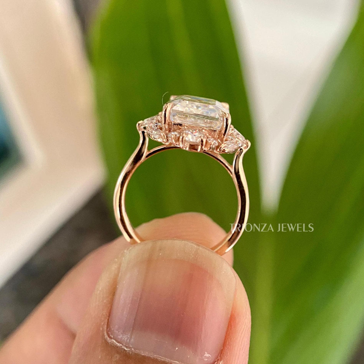 Halo setting engagement ring featuring a 3 CT emerald cut moissanite stone in prongs