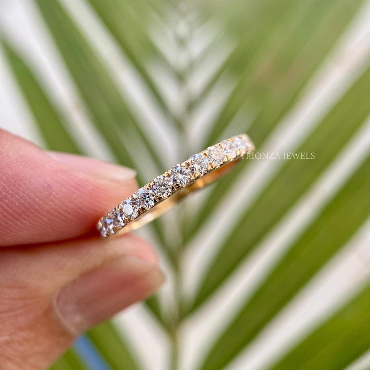 Micro pave moissanite wedding band showcasing round cut colorless stones set in prongs