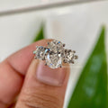 Oval cut moissanite three stone engagement ring with round prong side stones in gold