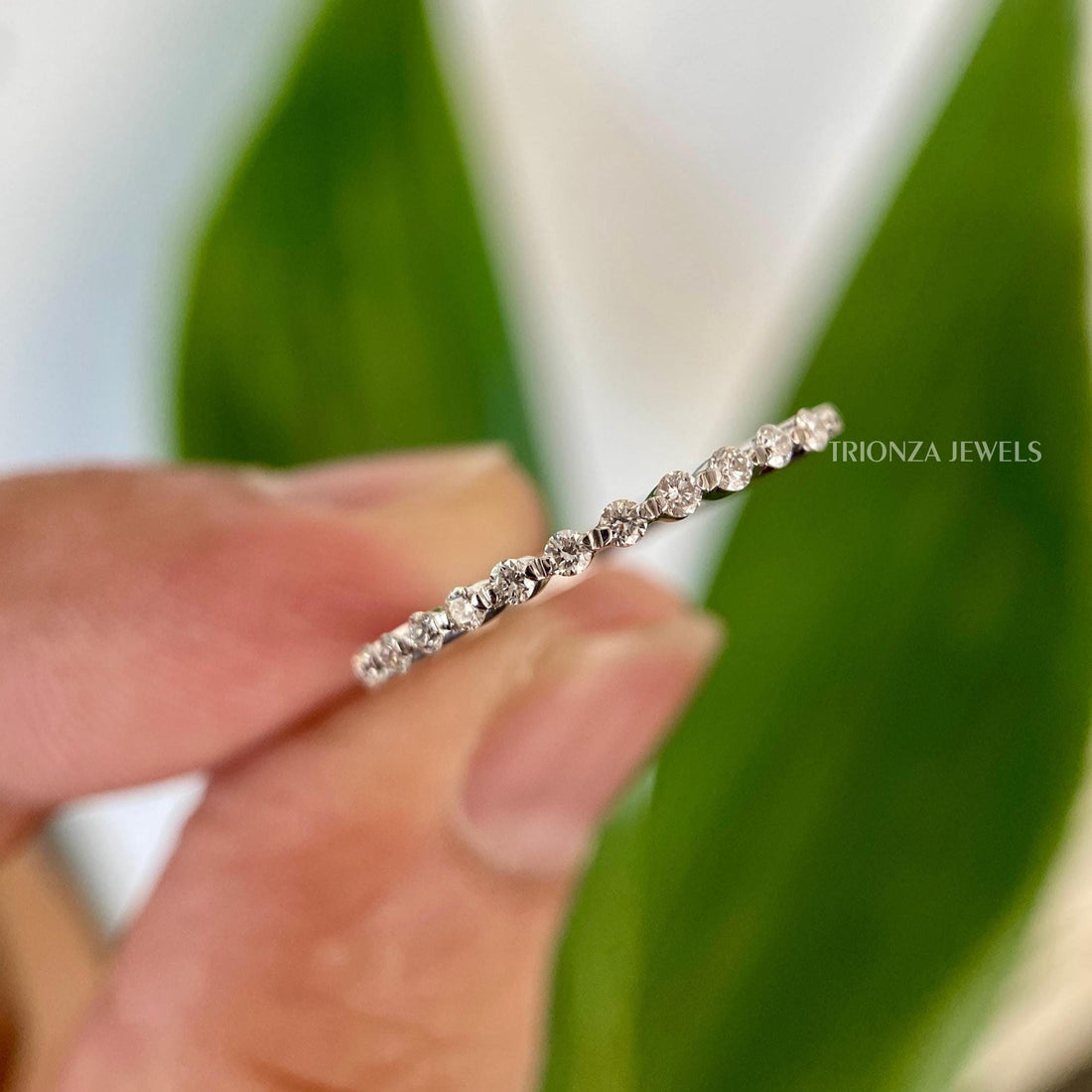 Round cut moissanite half eternity wedding band with shared prong setting shown up close