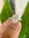 Oval cut moissanite three stone engagement ring featuring tapered baguette side stones in solid gold