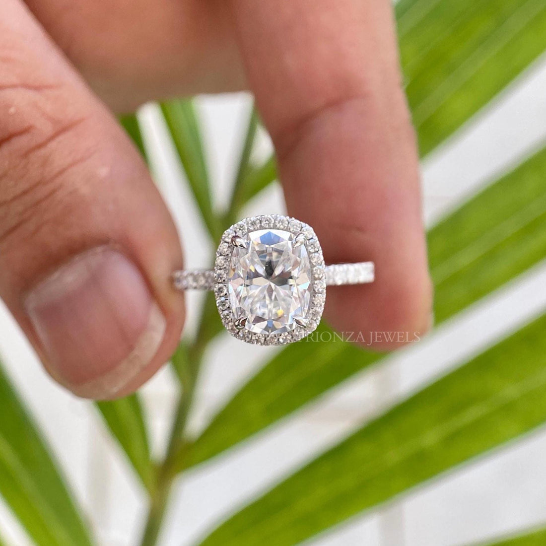 Cushion cut moissanite halo engagement ring featuring a pave set 14K gold band