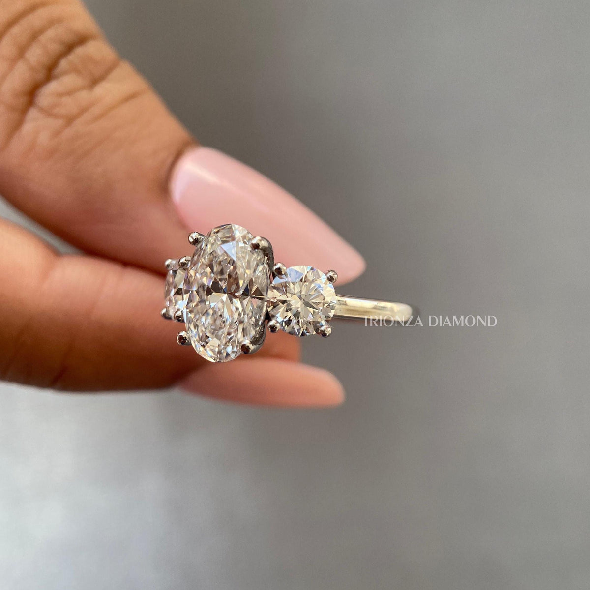 Round cut side diamonds set beside the oval center stone in an 18K white gold band