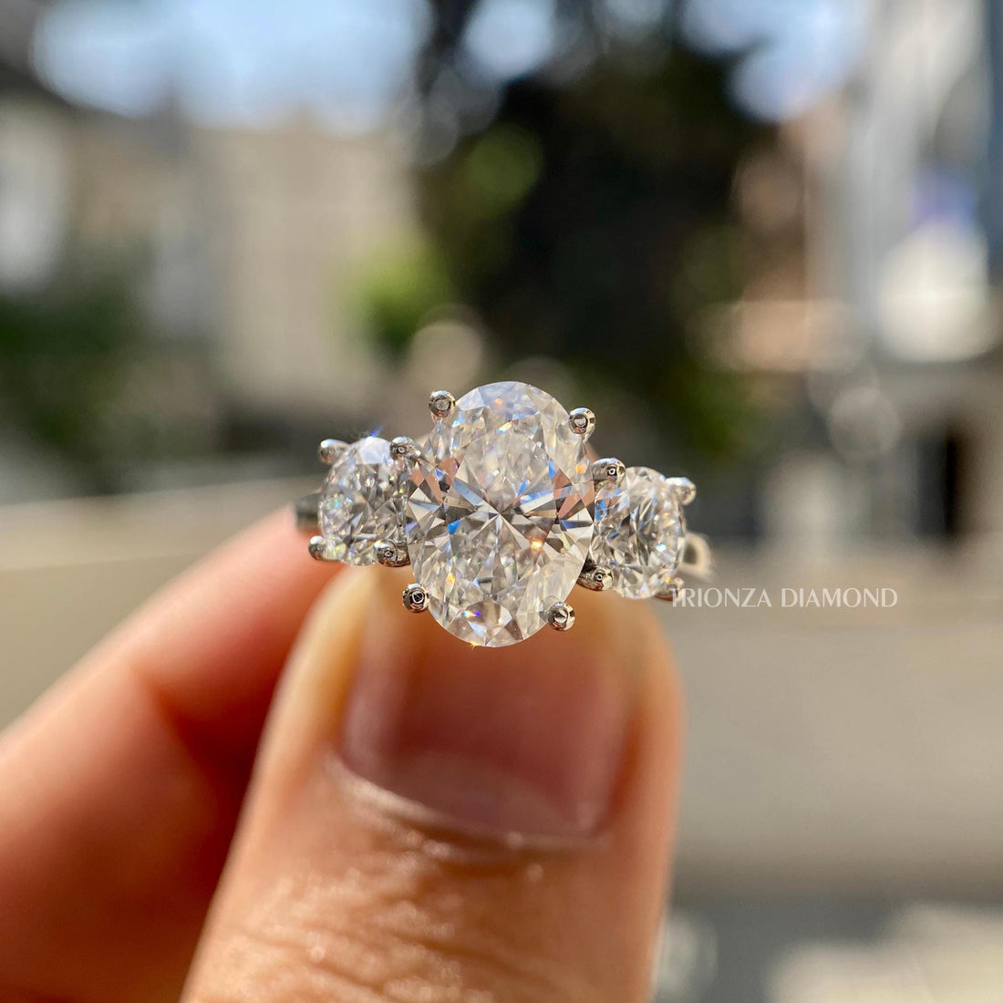 Oval lab grown diamond three stone engagement ring displayed with side round cut diamonds in 18K gold