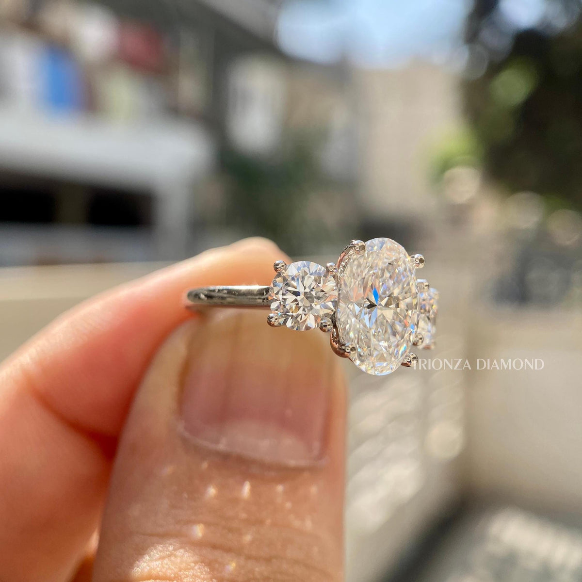 Side view of the oval cut center diamond flanked by round cut side stones in the setting