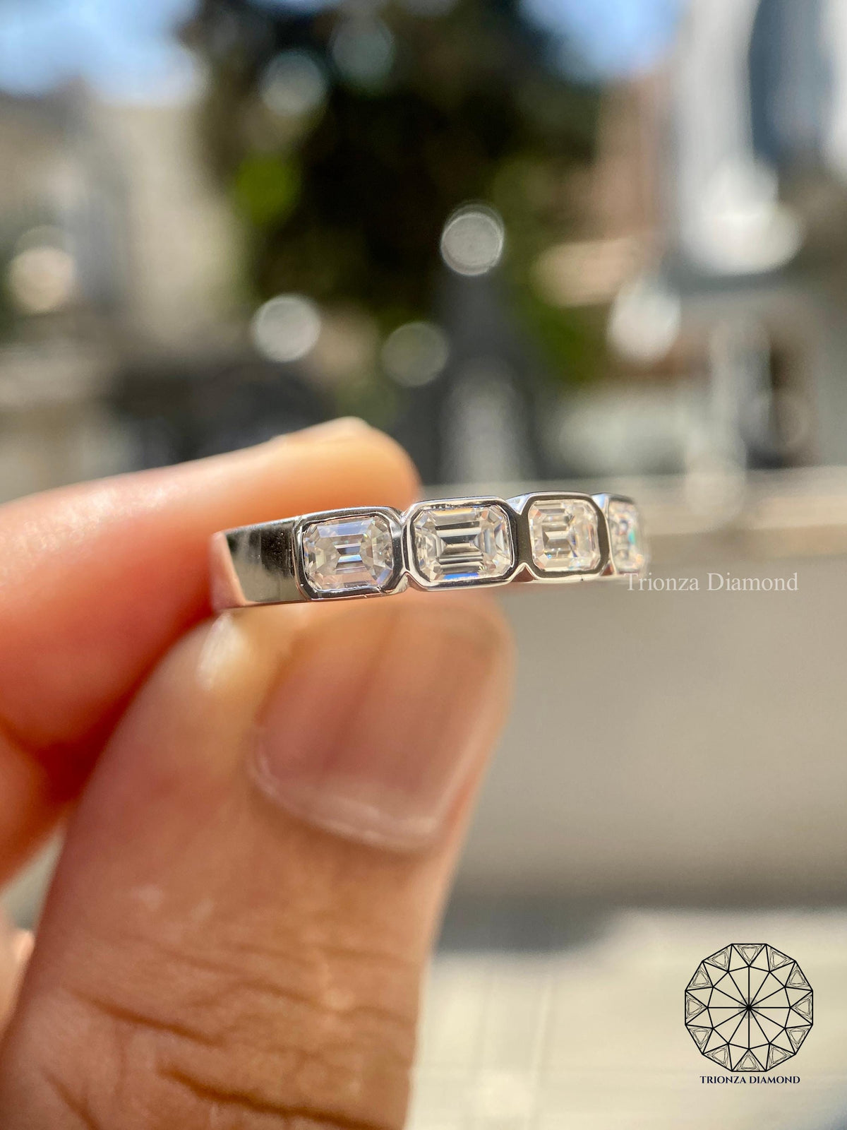 Woman wearing the stackable emerald cut diamond wedding band alongside other rings