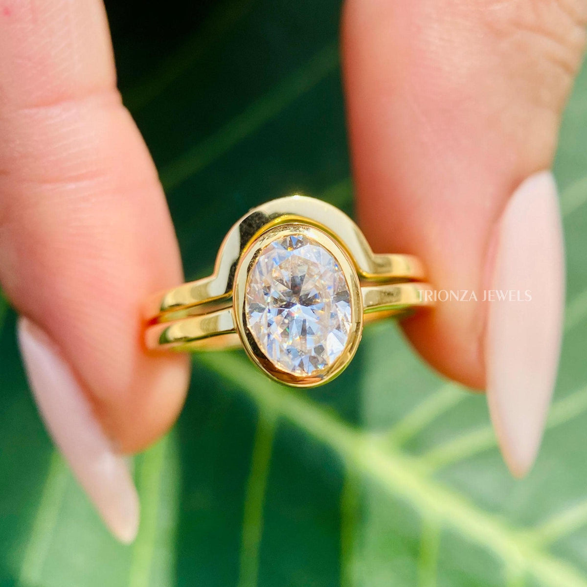 Oval moissanite bridal set featuring a bezel set solitaire ring and matching wedding band