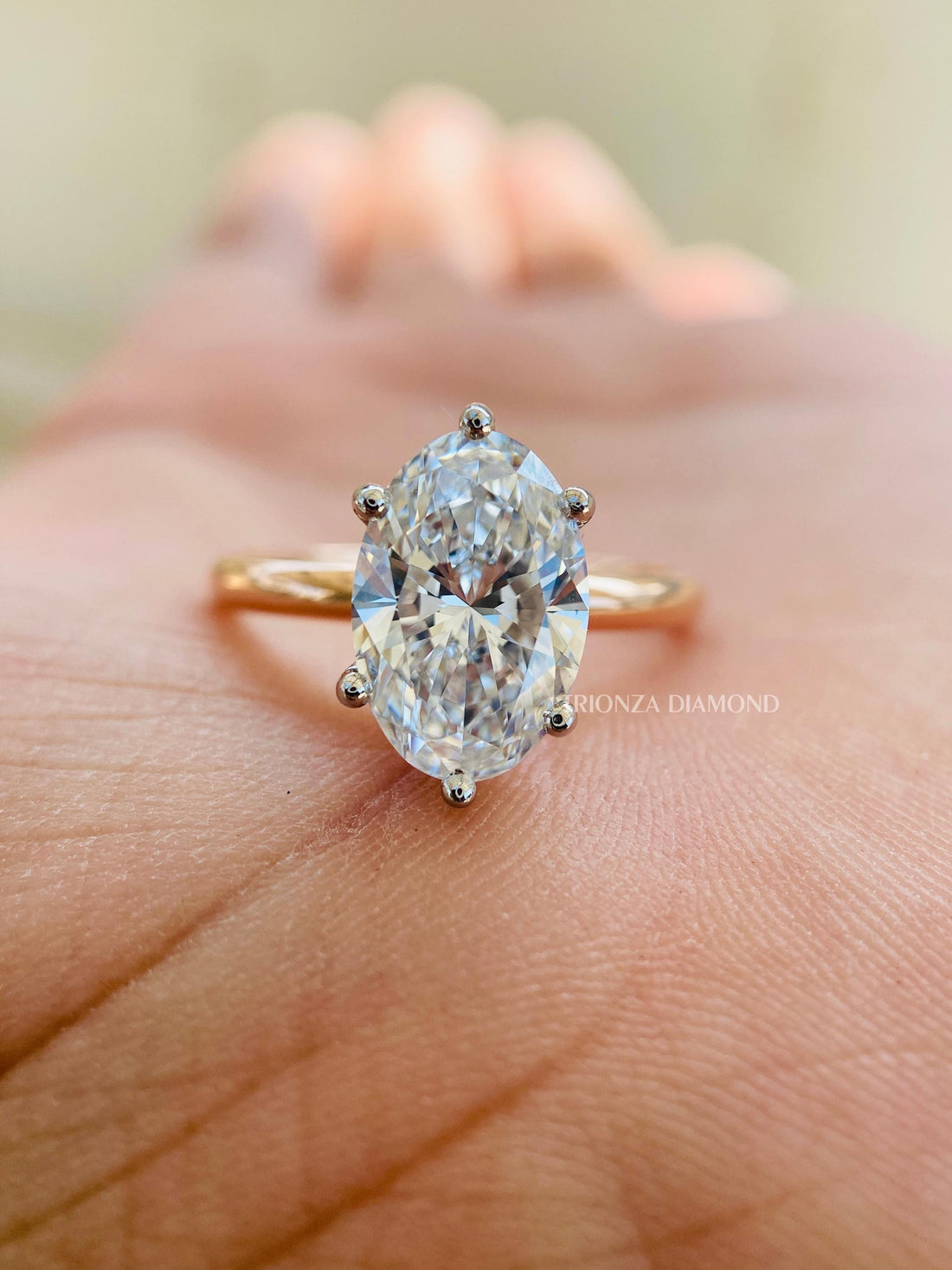 Oval lab grown diamond ring with a thin two-tone 14k gold band and solitaire setting