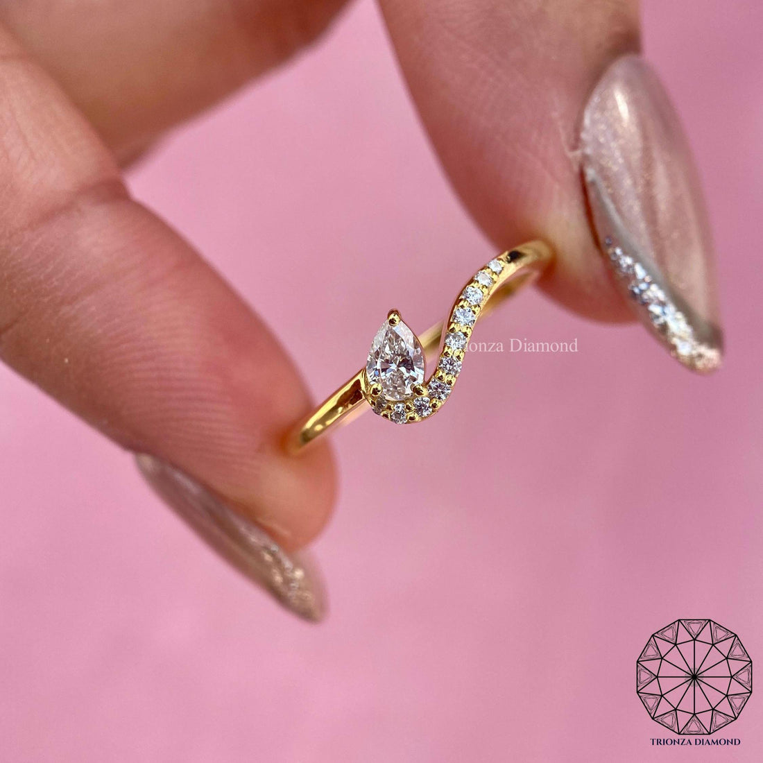 Pear cut lab grown diamond curved ring displayed to show its wavy 14k yellow gold band